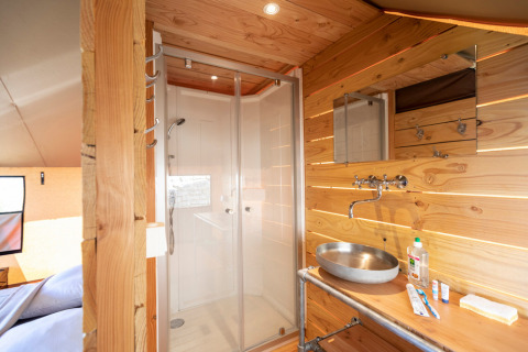 Interior del baño y ducha en la tienda safari Tente Trappeur Duo Village en Huttopia Lac de Rillé, Francia.