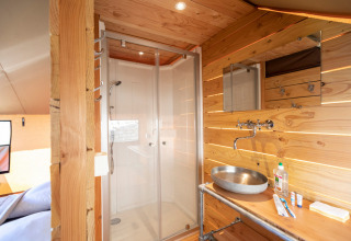 Interior del baño y ducha en la tienda safari Tente Trappeur Duo Village en Huttopia Lac de Rillé, Francia.