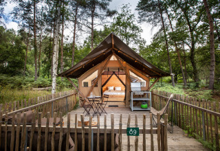 Safari tent Tente Trappeur Duo Village met houten terras in het bos bij Huttopia Lac de Rillé, Frankrijk.
