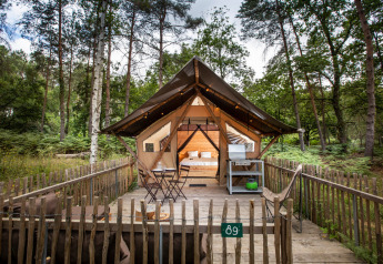 Tenda safari Tente Trappeur Duo Village con terrazza in legno nella foresta di Huttopia Lac de Rillé, Francia.