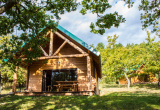 Chalets en bois entourés d’arbres au Village Huttopia Dieulefit, parc de vacances en Auvergne-Rhône-Alpes, France.