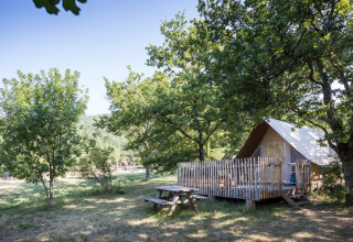 Lyst telt på terrasse blandt træer i ferieparken Huttopia Dieulefit i Auvergne-Rhône-Alpes, Frankrig.