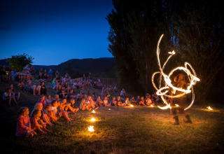 Kinderen bewonderen een avondlijke vuurshow in Village Huttopia Dieulefit in de openlucht in Frankrijk.