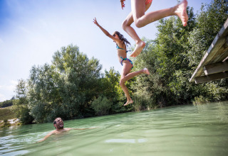 Children jump off a dock into a lake at Village Huttopia Dieulefit holiday park in Auvergne-Rhône-Alpes, France.