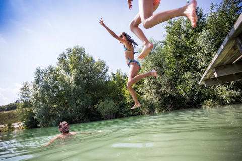 Bambini saltano da un pontile in un lago al Village Huttopia Dieulefit in Auvergne-Rhône-Alpes, Francia.