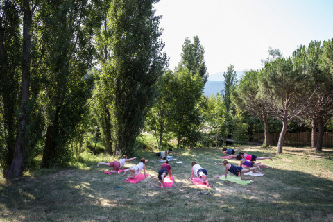 Buiten yogasessie aan Village Huttopia Dieulefit, omringd door bomen in Auvergne-Rhône-Alpes, Frankrijk.
