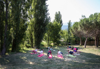 Outdoor-Yogastunde im Village Huttopia Dieulefit, umgeben von Bäumen, Auvergne-Rhône-Alpes, Frankreich.