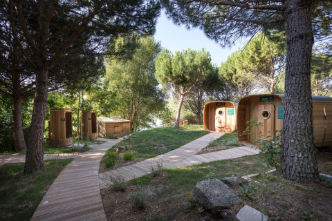 Cabañas de madera y pasarelas entre pinos en Huttopia Dieulefit, parque vacacional en Auvergne-Rhône-Alpes, Francia.