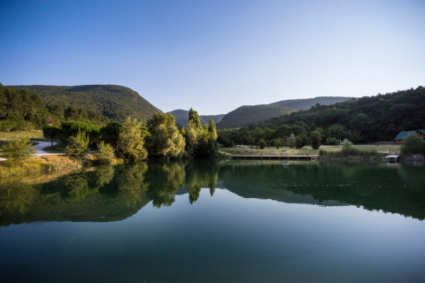 Lago tranquilo y montañas en el parque vacacional Village Huttopia Dieulefit en Auvergne-Rhône-Alpes, Francia.