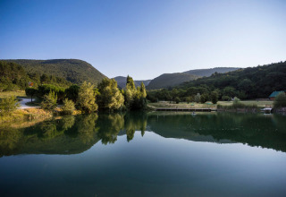 Peaceful lake and mountain scenery at Village Huttopia Dieulefit holiday park in Auvergne-Rhône-Alpes, France.