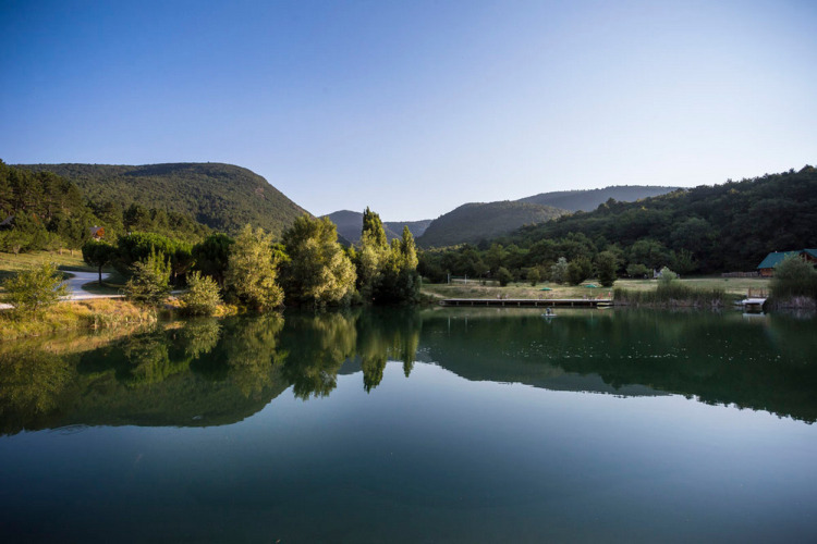 Ruhiger See mit Bergen im Hintergrund bei Village Huttopia Dieulefit in Auvergne-Rhône-Alpes, Frankreich.