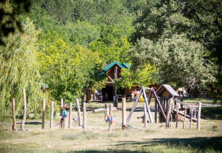 Kinderen spelen op een natuurlijk speelplein omringd door bomen in Village Huttopia Dieulefit, Auvergne-Rhône-Alpes.