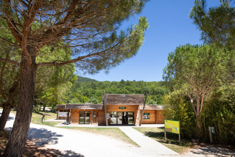 Entrada al parque vacacional Village Huttopia Dieulefit en Auvergne-Rhône-Alpes, Francia, rodeado de pinos.