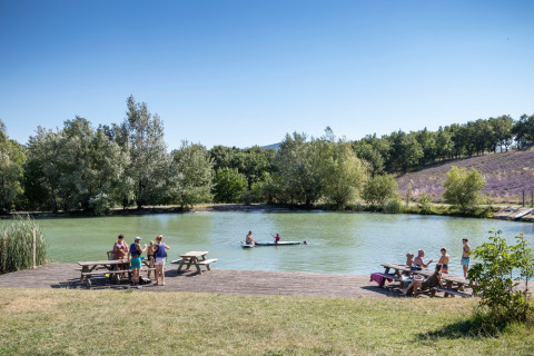 Personas relajándose y disfrutando de actividades al aire libre junto al lago en Village Huttopia Dieulefit, Auvergne-Rhône-Alpes, Francia.