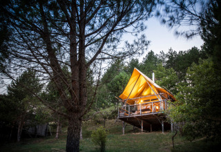 Verlichte hut op palen in het bos bij Village Huttopia Dieulefit, een vakantiepark in Auvergne-Rhône-Alpes, Frankrijk.