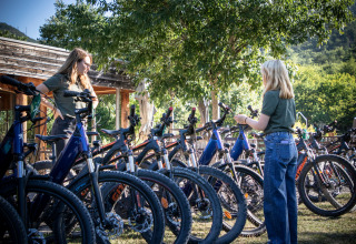 Zwei Personen betrachten Mountainbikes im Außenbereich des Feriendorfs Village Huttopia Dieulefit.
