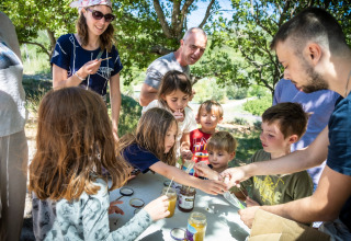 Kinderen en volwassenen beleven samen plezier buiten bij Village Huttopia Dieulefit in Auvergne-Rhône-Alpes, Frankrijk.