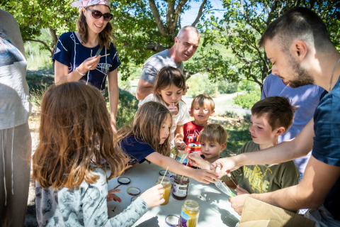 Kinderen en volwassenen beleven samen plezier buiten bij Village Huttopia Dieulefit in Auvergne-Rhône-Alpes, Frankrijk.