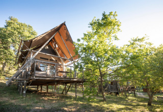 Verhoogde houten hut tussen bomen in Village Huttopia Dieulefit, Auvergne-Rhône-Alpes, Frankrijk.