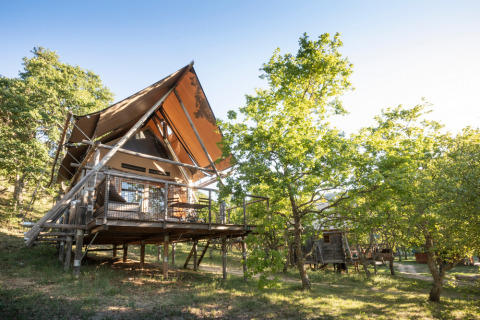 Verhoogde houten hut tussen bomen in Village Huttopia Dieulefit, Auvergne-Rhône-Alpes, Frankrijk.