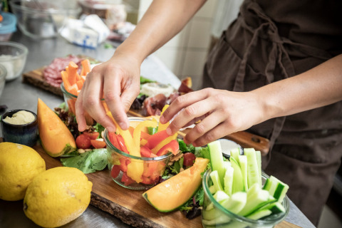 Persona preparando verduras y frutas frescas en una mesa de cocina en Village Huttopia Dieulefit, Auvergne-Rhône-Alpes.
