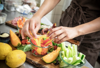 Persona che prepara verdure e frutta fresca sul tavolo a Village Huttopia Dieulefit, Auvergne-Rhône-Alpes.