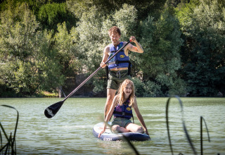 Twee personen doen aan suppen op een rustig meer bij Village Huttopia Dieulefit, Frankrijk.