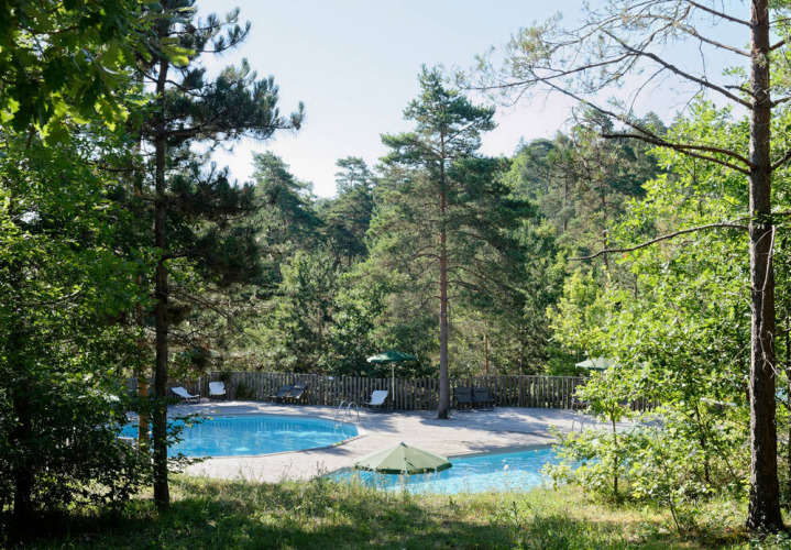 Piscine extérieure entourée de forêt et de transats au Village Huttopia Lanmary, Nouvelle-Aquitaine, France.