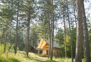 Blockhütten im sonnigen Wald des Feriendorfs Huttopia Lanmary in Nouvelle-Aquitaine, Frankreich.