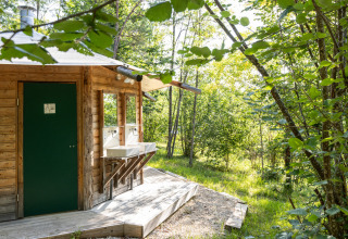 Træhytte med udendørs vaske i skovområdet ved Village Huttopia Lanmary, Nouvelle-Aquitaine, Frankrig.
