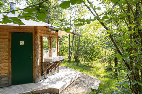 Cabaña de madera con lavabos exteriores en el bosque de Village Huttopia Lanmary, Nueva Aquitania, Francia.