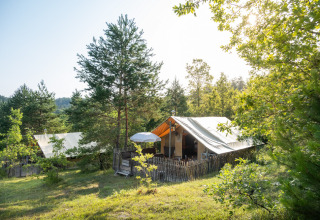Glamping telte blandt grønne træer i ferieparken Huttopia Lanmary, Nouvelle-Aquitaine, Frankrig, en solrig dag.