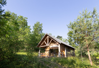 Wooden cabin in lush forest at Village Huttopia Lanmary holiday park, Nouvelle-Aquitaine, France