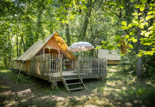 En hyggelig glamping-teltlejr med en træterrasse i en grøn skov ved Village Huttopia Lanmary, Nouvelle-Aquitaine.