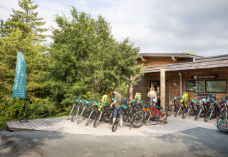 Cykeludlejning ved træhytte i Village Huttopia Lanmary feriepark, omgivet af natur i Frankrig.