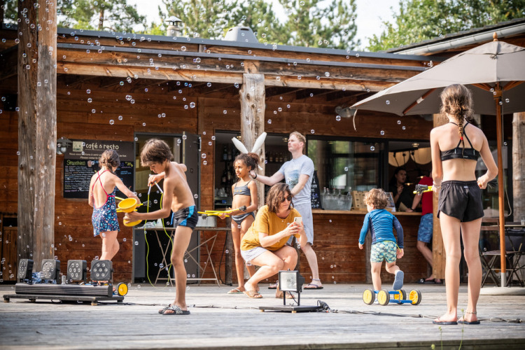 Des enfants jouent avec des bulles devant un chalet au Village Huttopia Lanmary, Nouvelle-Aquitaine, France.