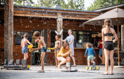 Children play with bubbles outside a wooden lodge at Village Huttopia Lanmary, Nouvelle-Aquitaine, France.