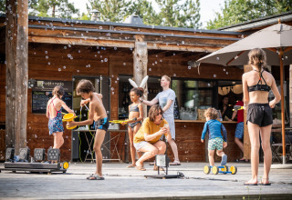 Des enfants jouent avec des bulles devant un chalet au Village Huttopia Lanmary, Nouvelle-Aquitaine, France.