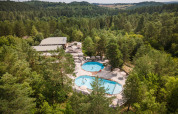 Luftfoto af Village Huttopia Lanmary feriepark med to swimmingpools omgivet af skov i Nouvelle-Aquitaine.