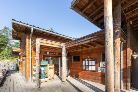 Wooden lodge at Village Huttopia Lanmary holiday park in Nouvelle-Aquitaine, France, under clear sky.
