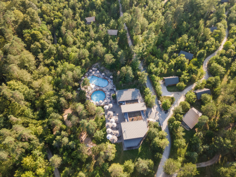 Aerial view of Village Huttopia Lanmary holiday park in Nouvelle-Aquitaine, France, showing pool and cabins in forest.