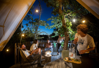 Cinq amis partagent un moment convivial avec repas et boissons sur la terrasse d'une tente safari.