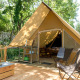 Tienda safari con terraza de madera y zona de estar acogedora, rodeada de bosque para glamping.