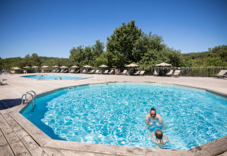Solrige swimmingpools med solsenge på træterrasse i Village Huttopia Sud-Ardèche, Auvergne-Rhône-Alpes, Frankrig.