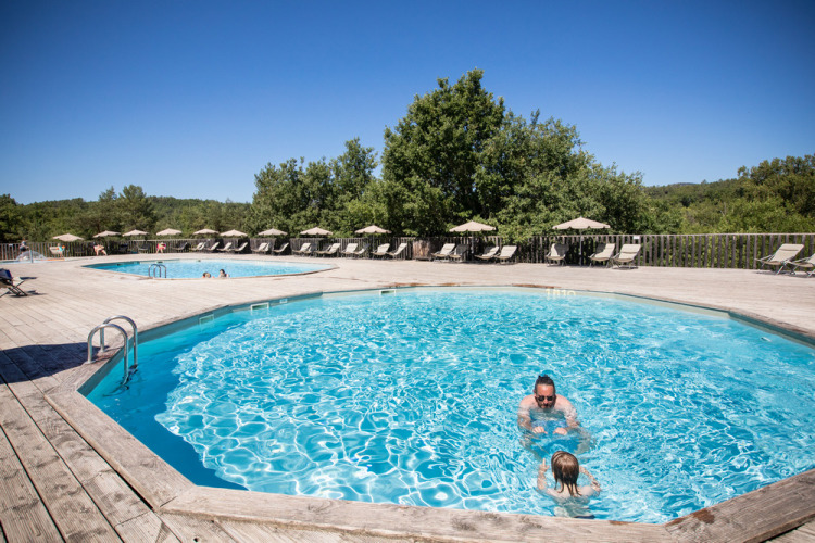 Piscines en plein air avec transats au Village Huttopia Sud-Ardèche, région Auvergne-Rhône-Alpes, France.