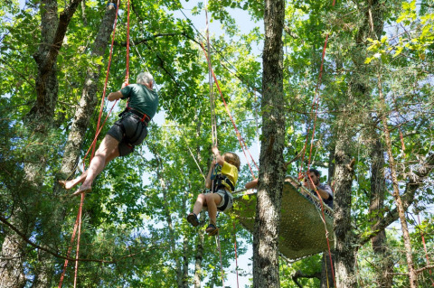 Persone che arrampicano sugli alberi con corde a Village Huttopia Sud-Ardèche, Auvergne-Rhône-Alpes.