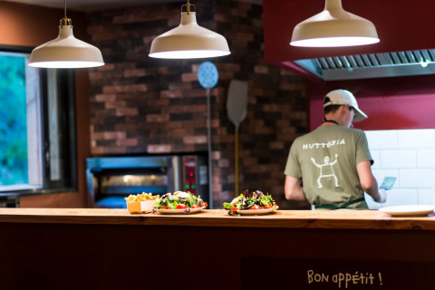 Een kok werkt in een open keuken met verse salades op de toonbank in Village Huttopia Sud-Ardèche.