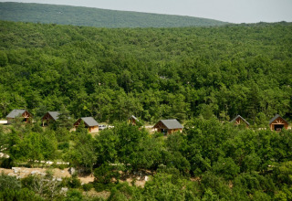 Holzhütten eingebettet im grünen Wald im Village Huttopia Sud-Ardèche in Auvergne-Rhône-Alpes, Frankreich.
