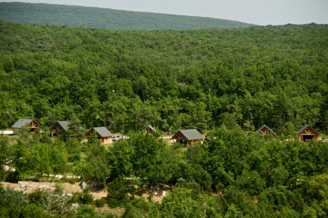 Cabañas de madera entre frondosos árboles en Village Huttopia Sud-Ardèche, Auvergne-Rhône-Alpes, Francia.