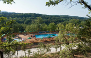 Luftfoto af poolområde omgivet af træer i feriebyen Huttopia Sud-Ardèche, Auvergne-Rhône-Alpes, Frankrig.